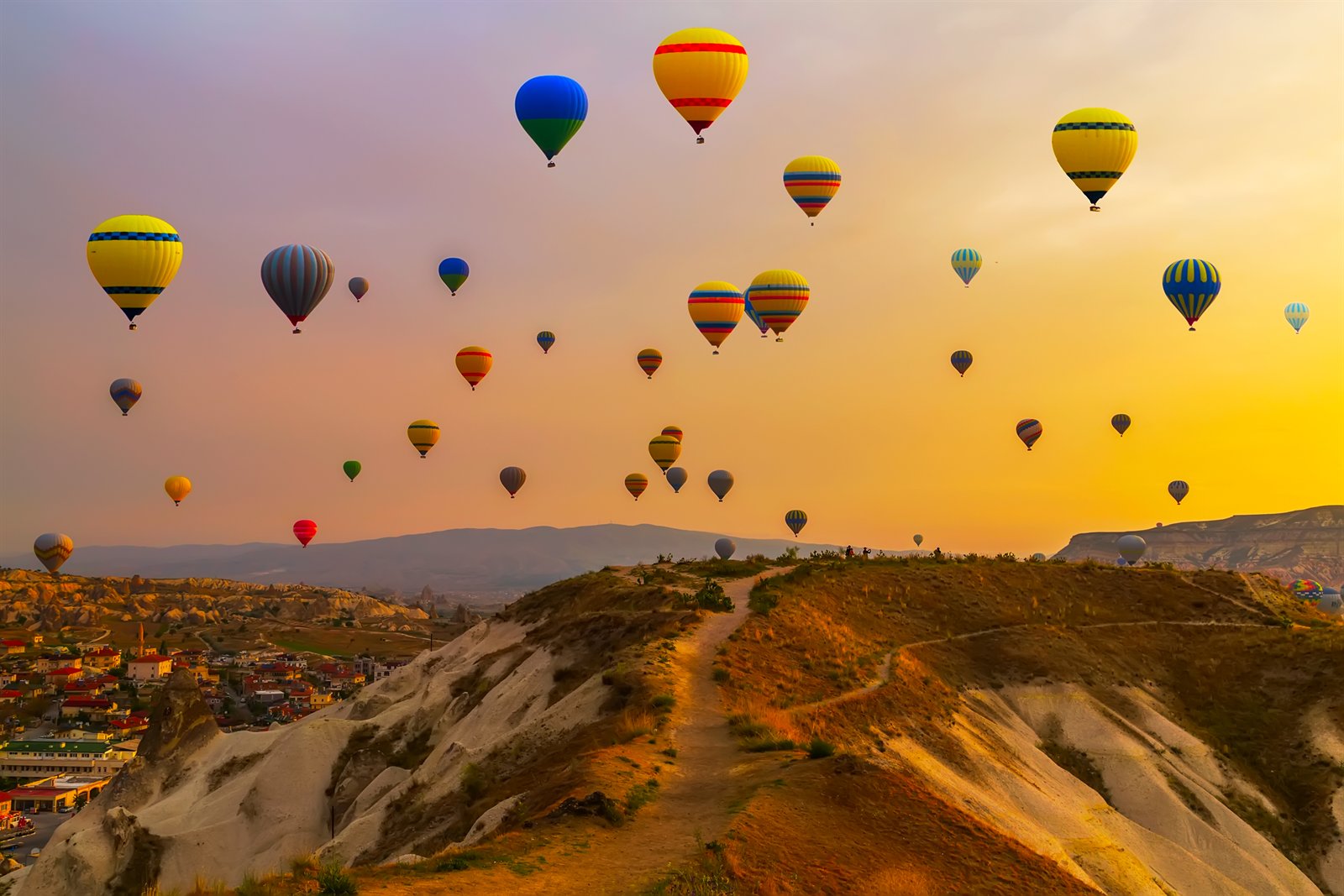 Hot-air balloons drifting over the tufa ridges and valleys of Cappadocia at sunrise